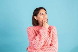 femme brune avec un pull rose qui réfléchit
