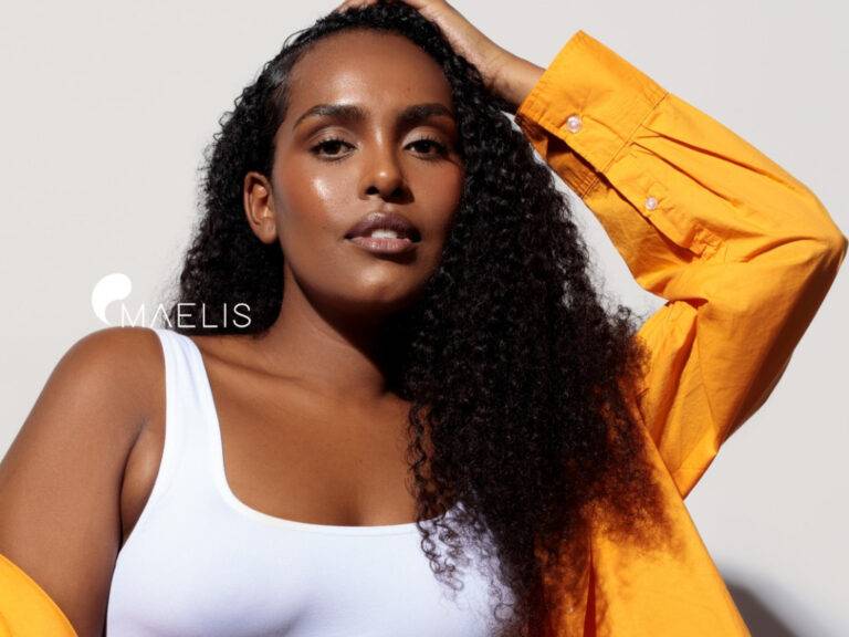 Femme à la peau foncée vêtu d'une chemise orange et un top blanc